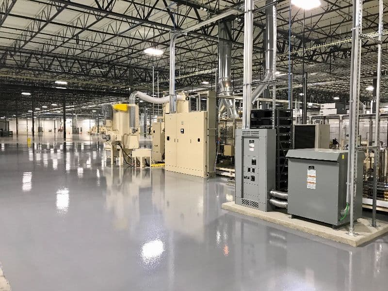 Industrial facility interior with machinery, polished floors, and extensive ventilation system.