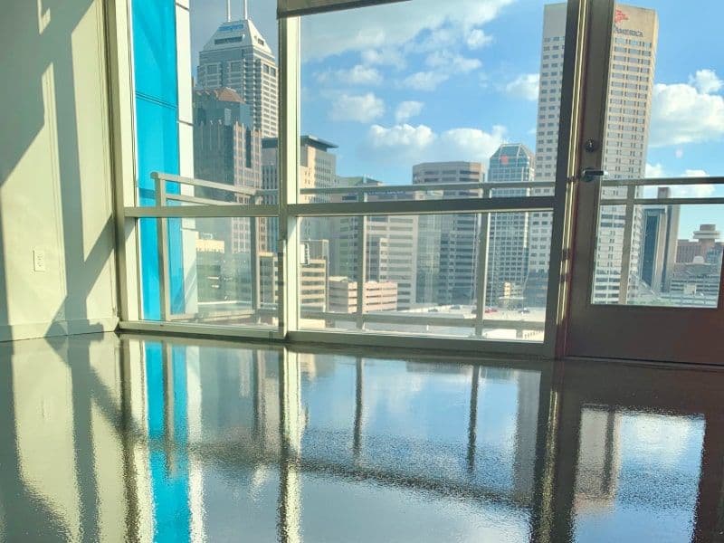 Modern residential interior with polished floor and city skyline view through large windows.