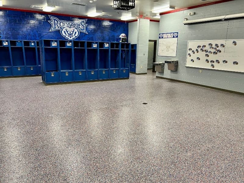 Royal high school locker room with blue lockers, team logo, and clean flooring.