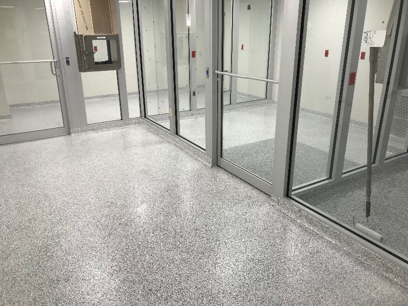 Newly finished clean room with polished gray vinyl flooring and large glass doors.