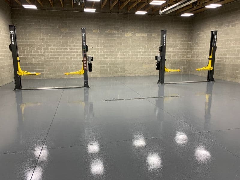 Clean, modern garage with four hydraulic car lifts and newly coated concrete floor.