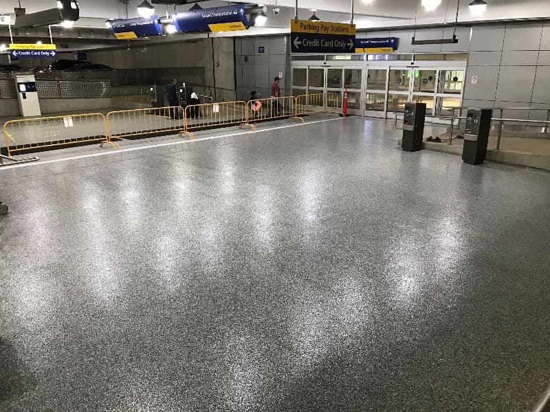 Empty parking structure floor with credit card payment machines and signage in view.