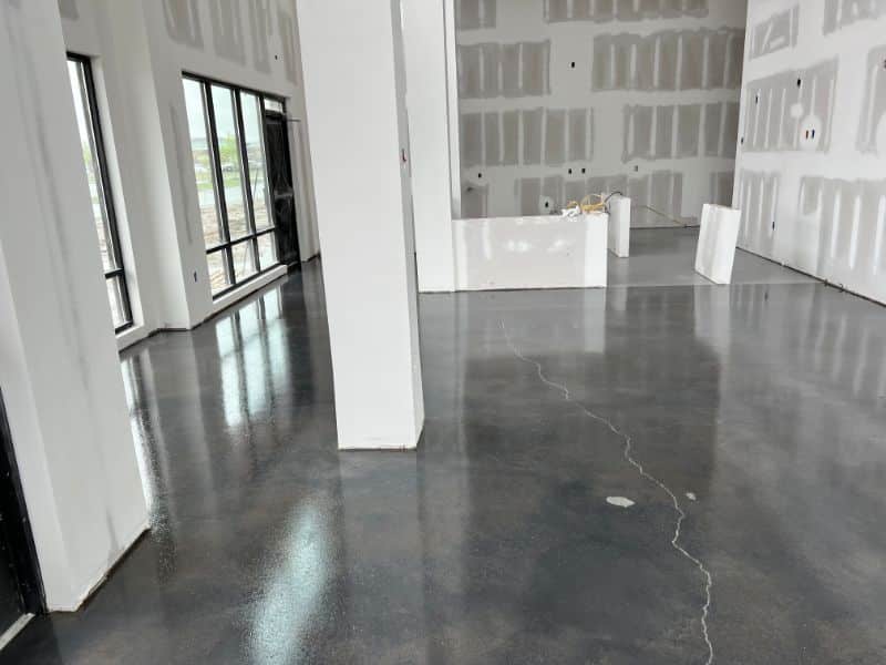 Modern interior space with glossy polished concrete floor and unfinished drywall walls.