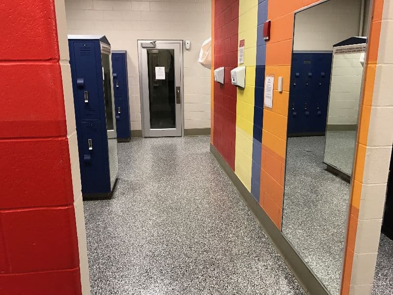Interior view of a colorful locker room with blue lockers, mirrors, and tiled flooring.