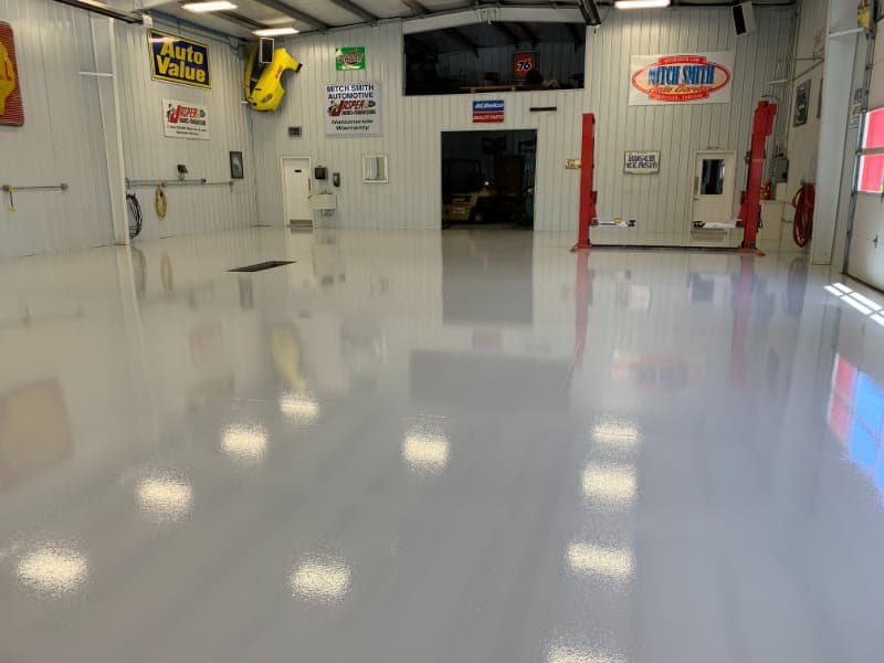 Auto repair shop interior with glossy epoxy floor, shop equipment, and signage.