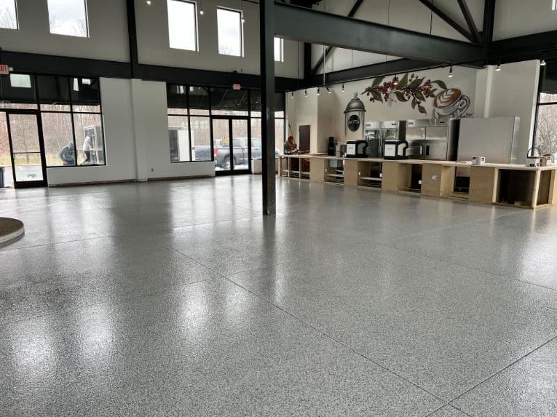 Spacious cafe interior with polished concrete floor and large windows. Light and modern design.