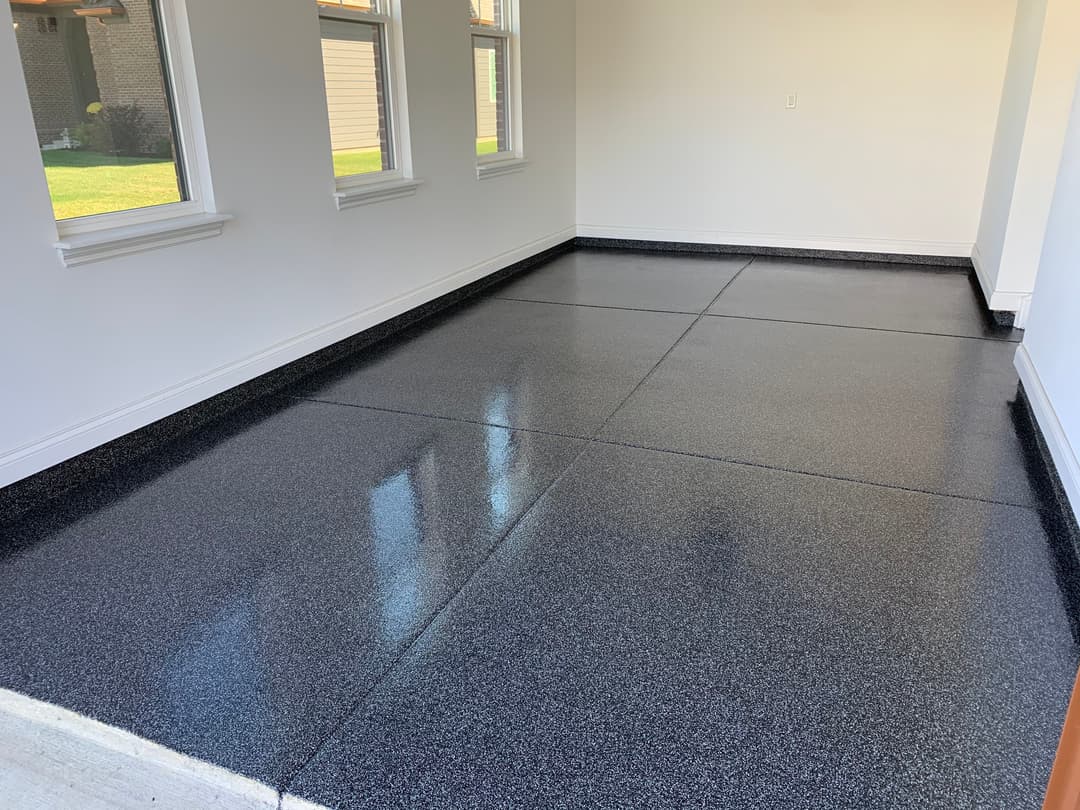 Glossy black epoxy floor in well-lit, empty room with large windows.