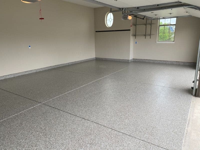 Clean, polished garage floor with gray epoxy finish and natural light.