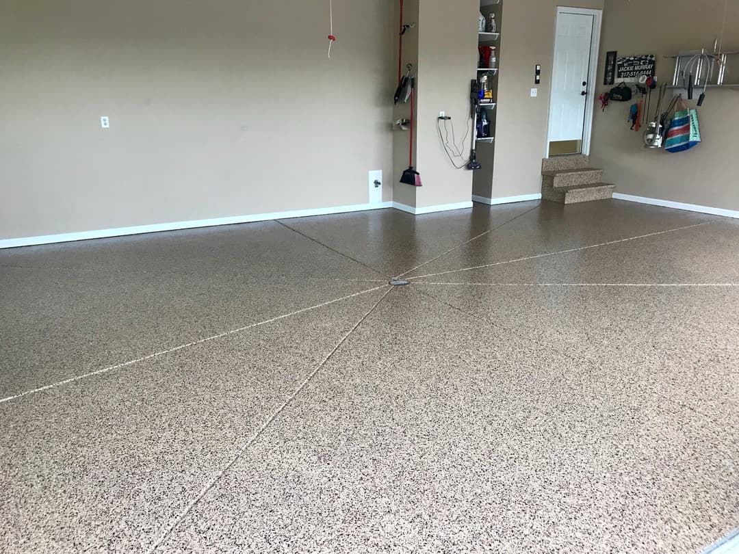 Clean garage interior with polished epoxy floor, stairs, and organized storage options.