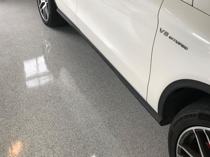 White luxury car with V8 Biturbo badge on polished garage floor.