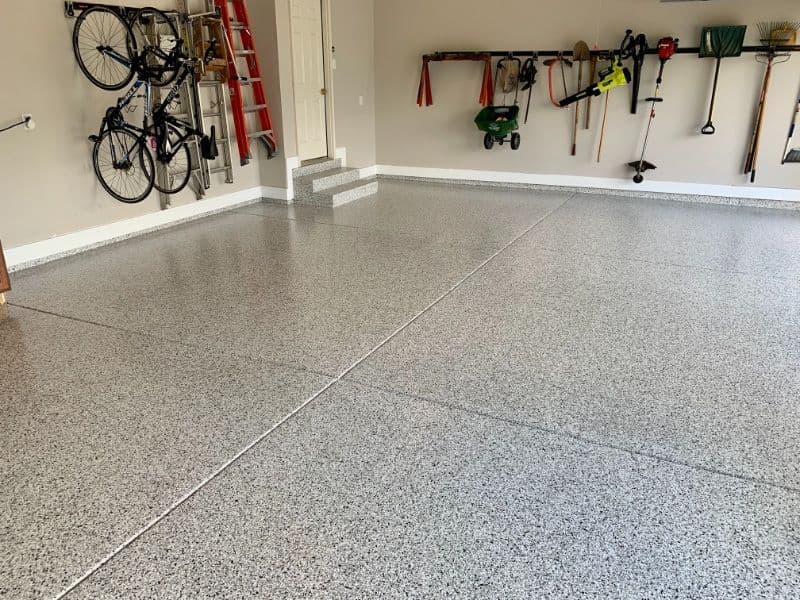 Clean and polished garage floor with organized tools and bikes on the walls.