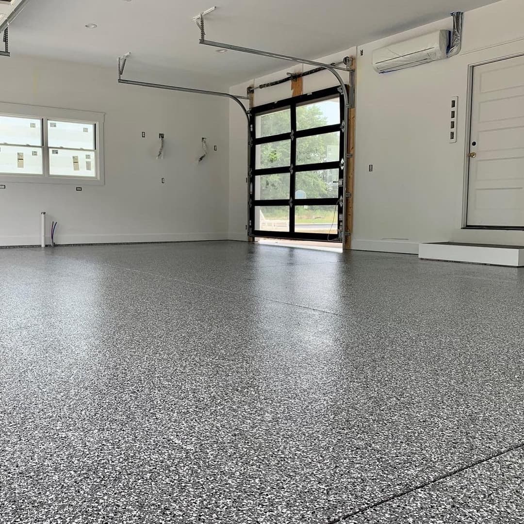 Clean, newly renovated garage interior with speckled flooring and large glass garage door.