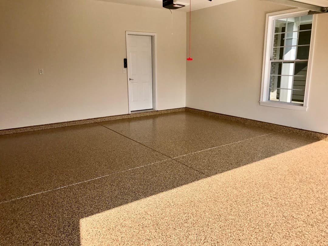 Clean and spacious garage interior with epoxy floor and natural light from windows.