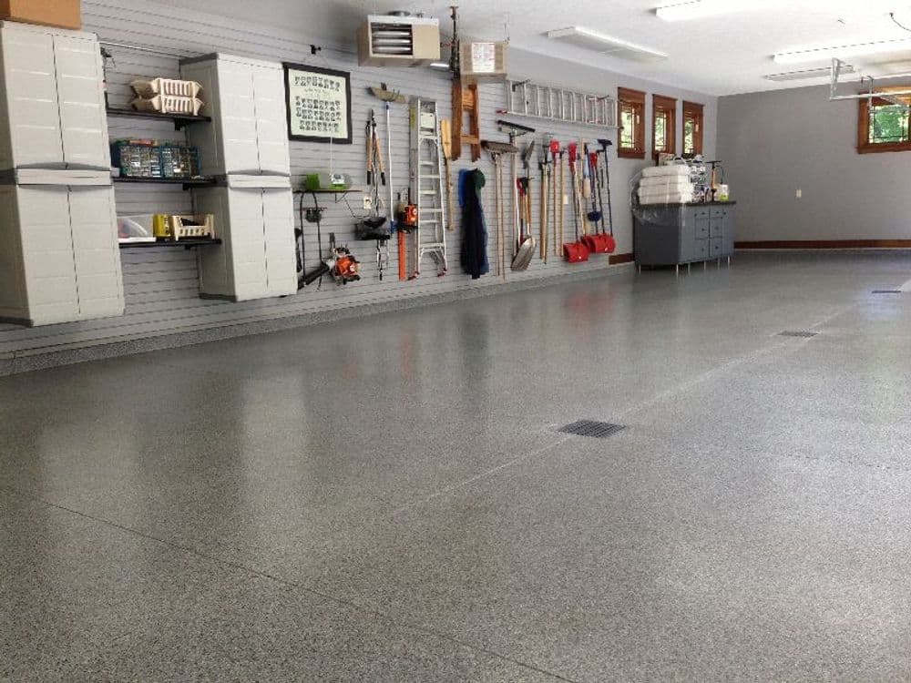 Spacious, organized garage with storage cabinets, tools, and a polished floor.