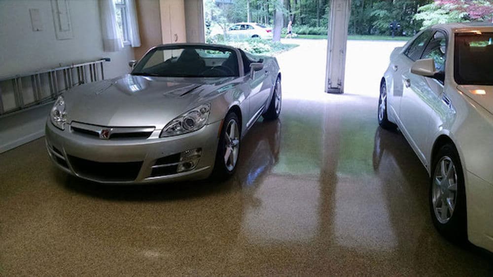 Silver convertible sports car parked in a bright garage with polished floor and natural light.
