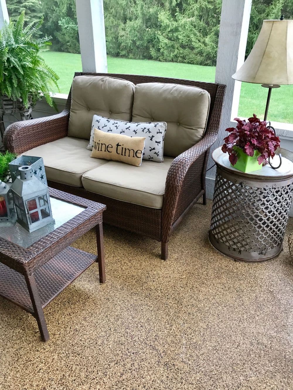 Cozy outdoor seating with a "wine time" pillow, lanterns, and potted plants on a porch.
