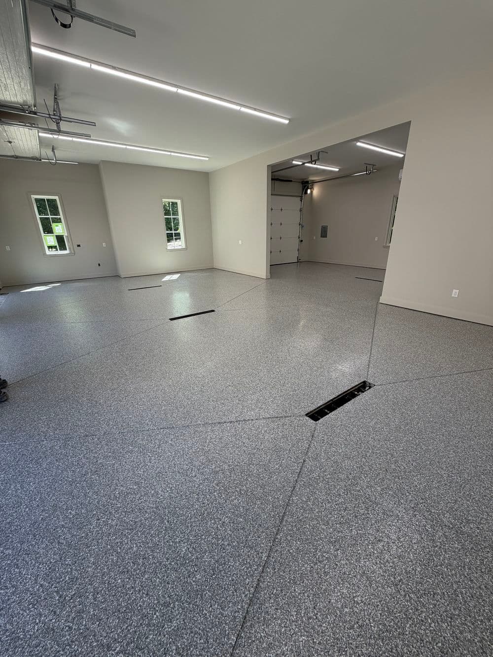 Spacious, newly finished garage with gray epoxy flooring and bright overhead lighting.